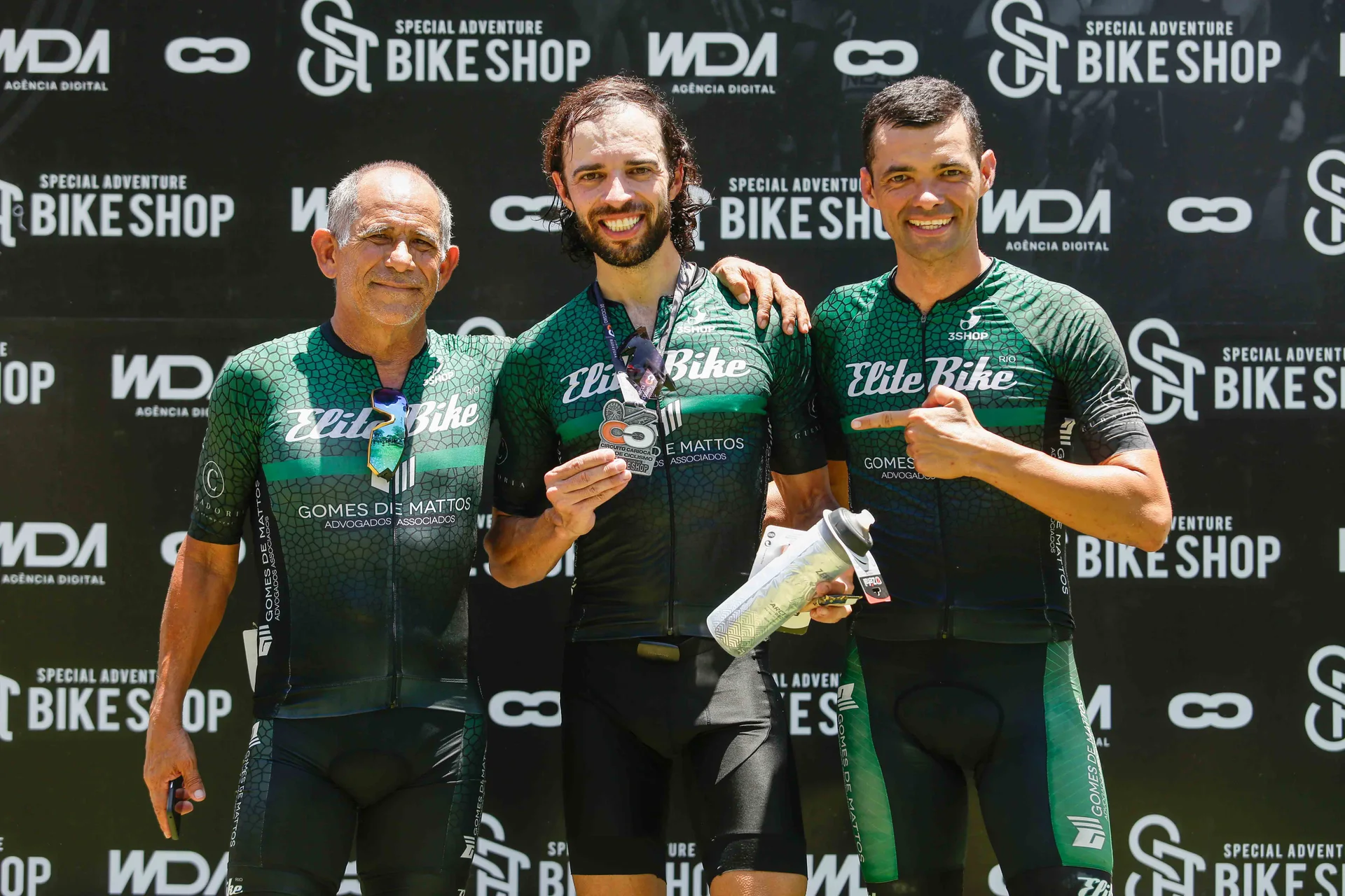 Integrantes da equipe posam diante do painel com as marcas do evento.