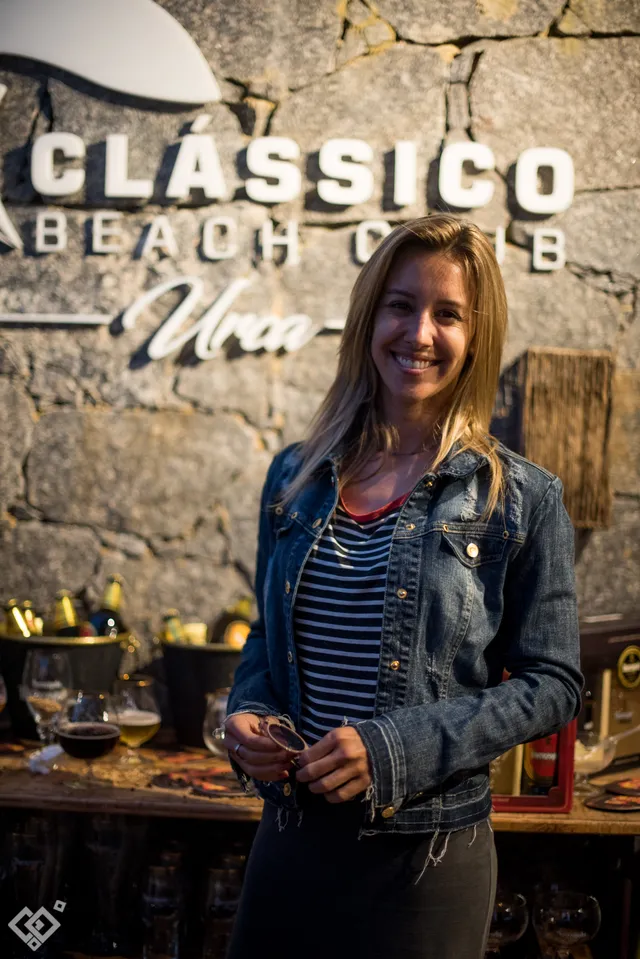 Mulher com uma taça diante da assinatura do Classico Beach Club.
