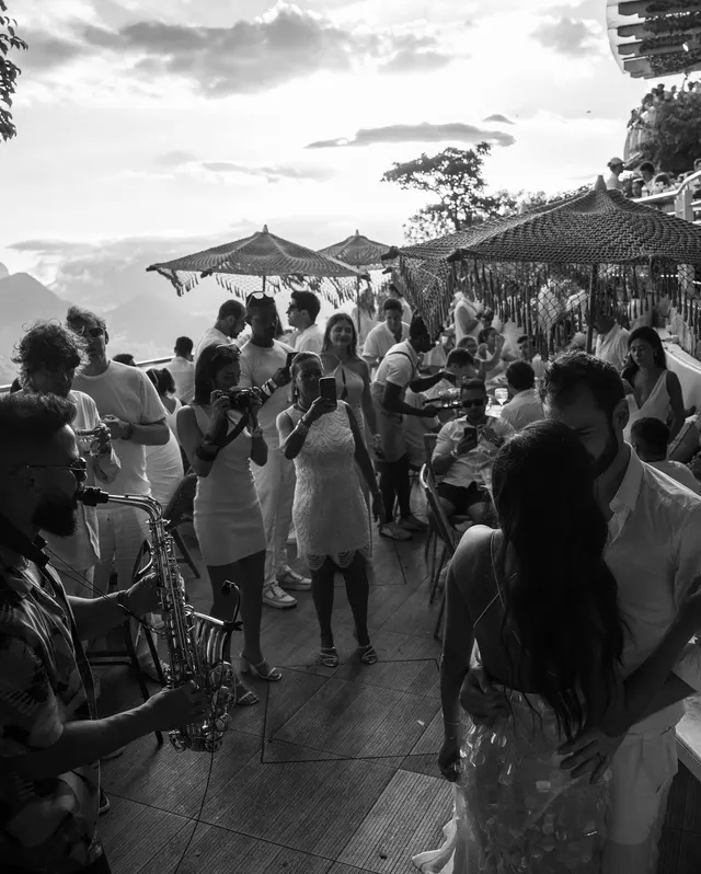 Pessoas reunidas no beach club em fotografia em preto e branco.