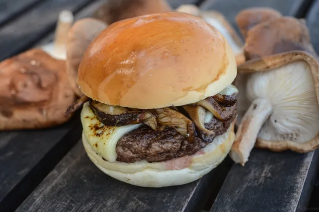 Hambúrguer com queijo e cogumelos sobre uma tábua.