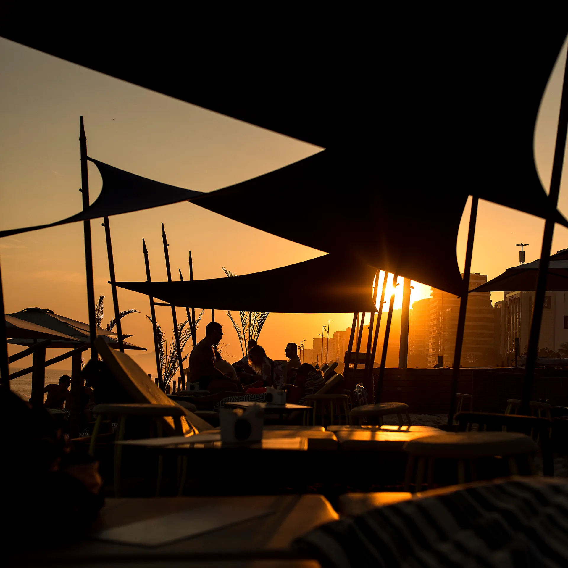 Luz do pôr do sol entre os ombrelones do beach club.