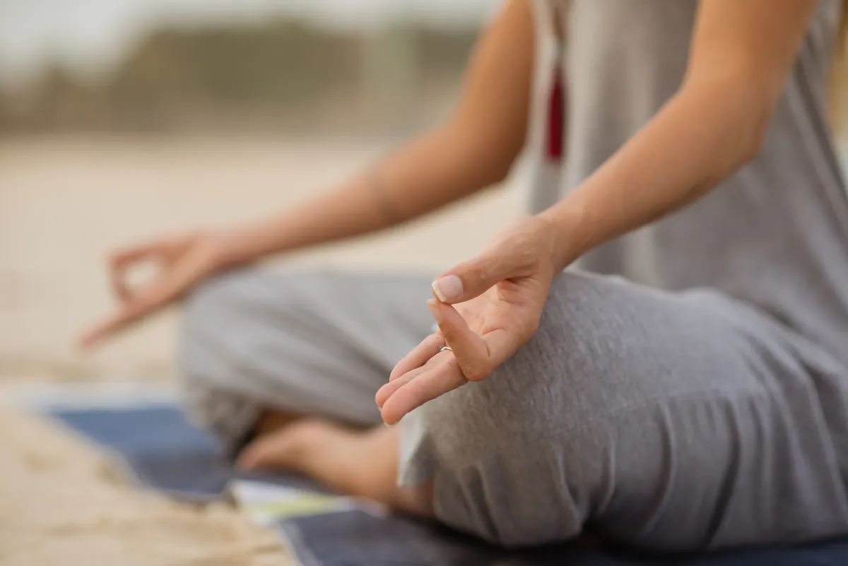 Mãos em posição de meditação, apoiadas nos joelhos.
