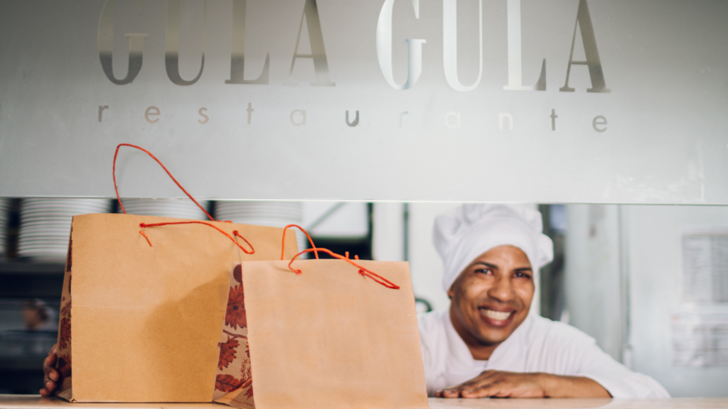 Colaboradora do Gula Gula entregando pedidos embalados.