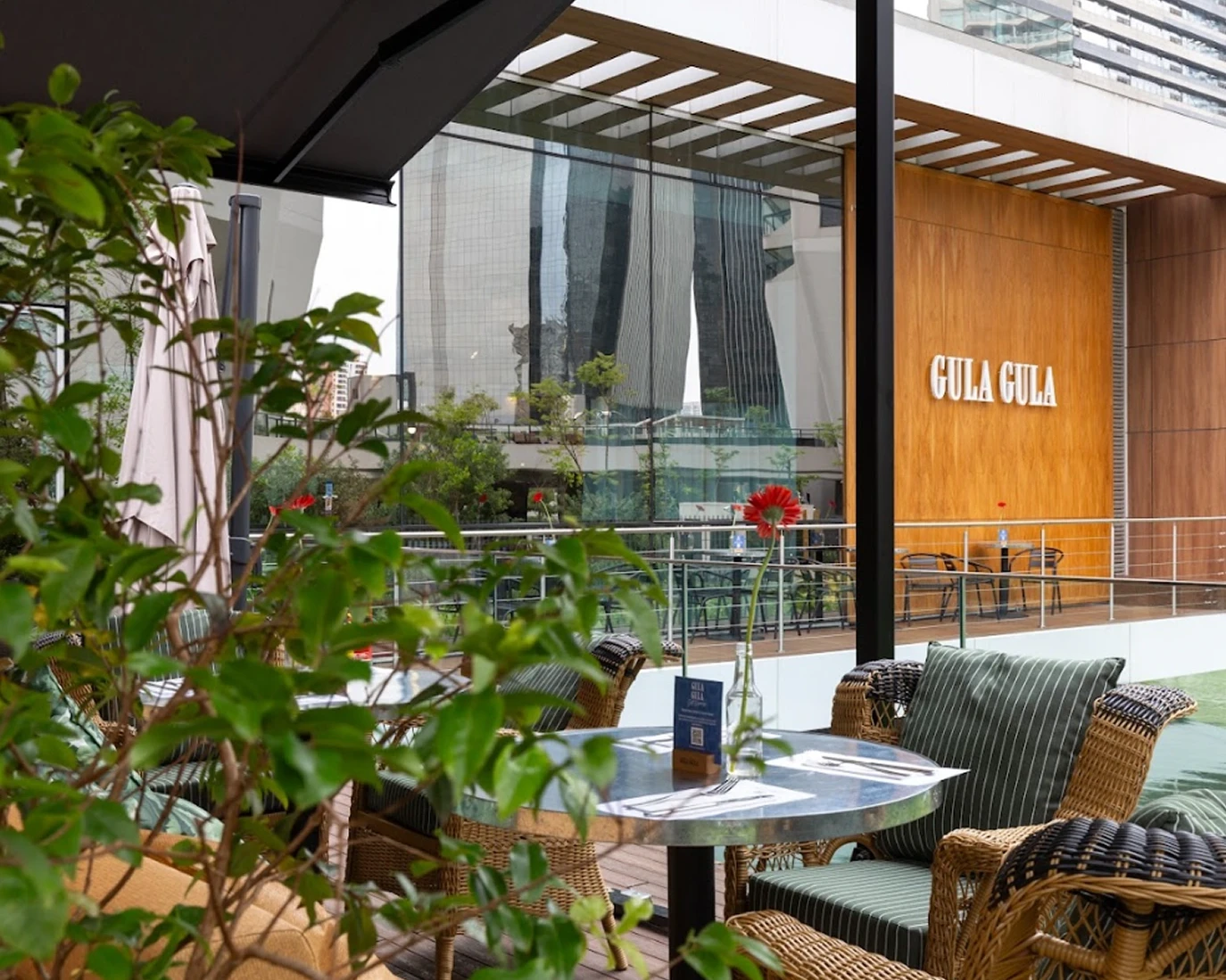 Varanda de uma unidade Gula Gula com mesas, plantas e vista para a cidade.