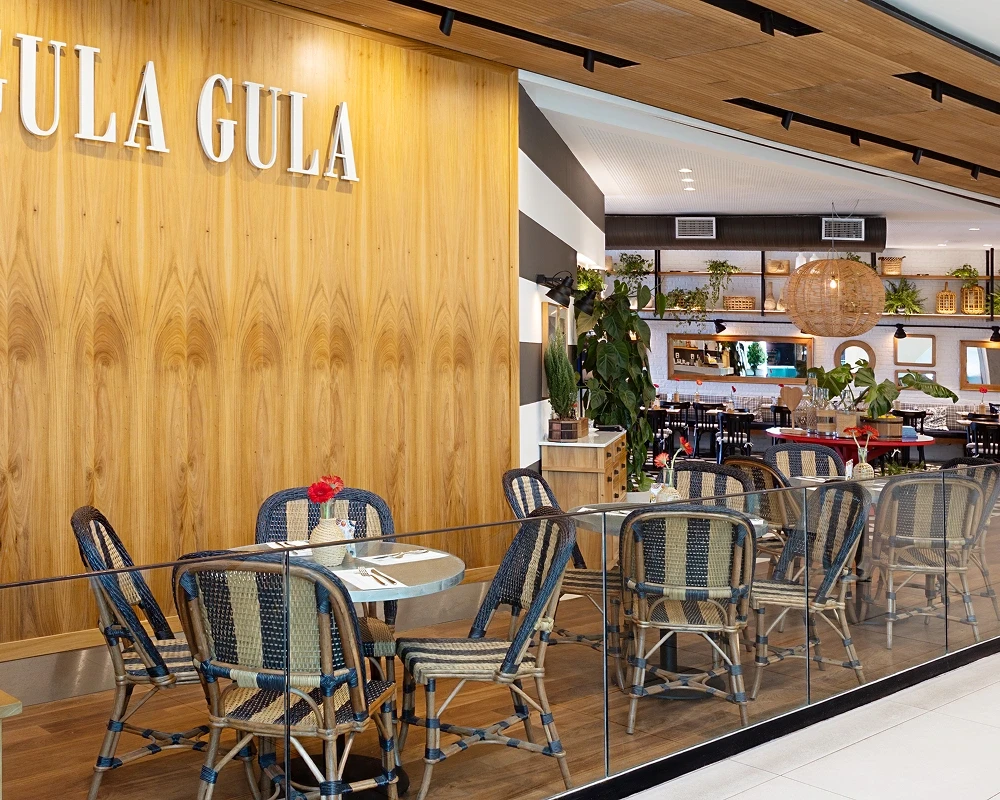 Unidade Gula Gula com fachada de madeira e área externa.
