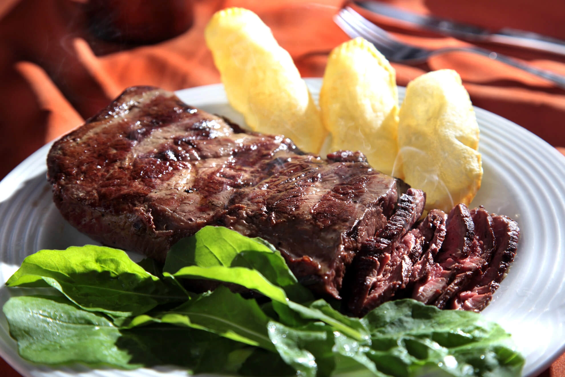 Carne na brasa com acompanhamentos em fotografia publicada no site da Majórica Rio.